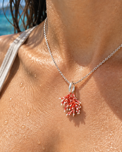 Red coral pendant necklace in 950 sterling silver, worn on wet skin with a coral reef background
